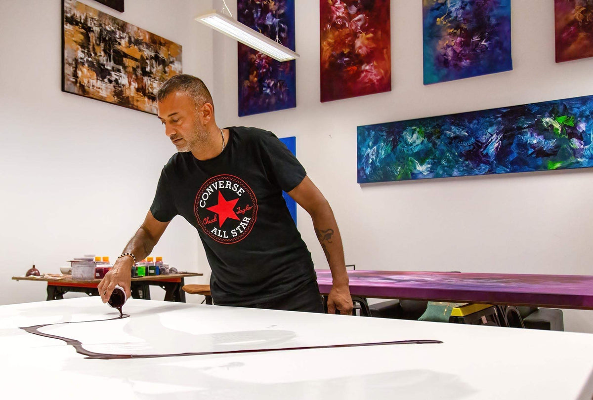 Vibrant abstract paintings on display in gallery with an artist at work on a large canvas