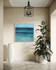 Serene coastal abstract art: Vibrant blue and green seascape painting in modern entryway with plant decor.