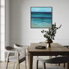 Serene abstract seascape painting in modern dining room. Framed artwork depicting tranquil ocean and sky in shades of blue and green. Rustic wooden dining table with chairs and a vase of fresh flowers, creating a peaceful and inviting atmosphere.