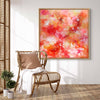 Colorful abstract painting on a wall above a wicker chair with a blanket in a room.
