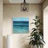 Abstract Seascape | Serenity 30x30" - Vibrant abstract painting of a serene ocean landscape, displayed in a modern home interior with a potted plant and a decorative light fixture.