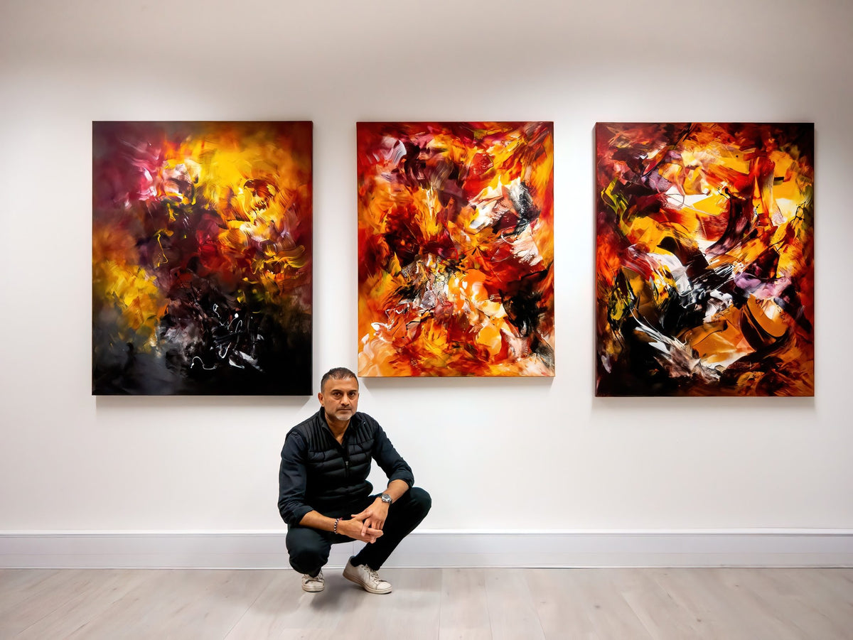 Paresh Nrshinga FRSA in his London studio beneath three original red, orange and gold abstract paintings
