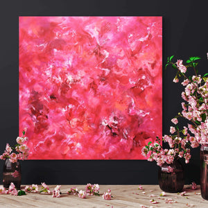 Vibrant abstract painting featuring swirls of pink and red hues, surrounded by vases of delicate pink flowers on a wooden surface